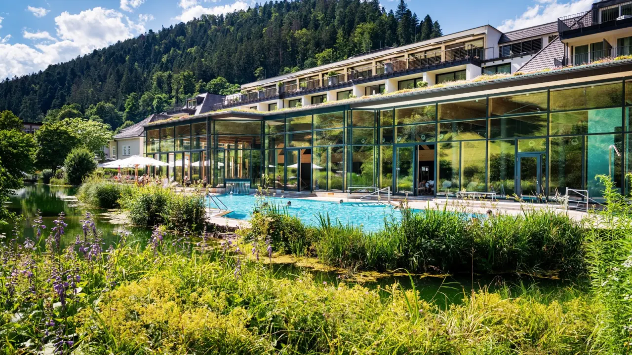 Grosszügiger Aussenpoolbereich mit Glasfassade und umgebender Natur im Hotel Therme Bad Teinach.