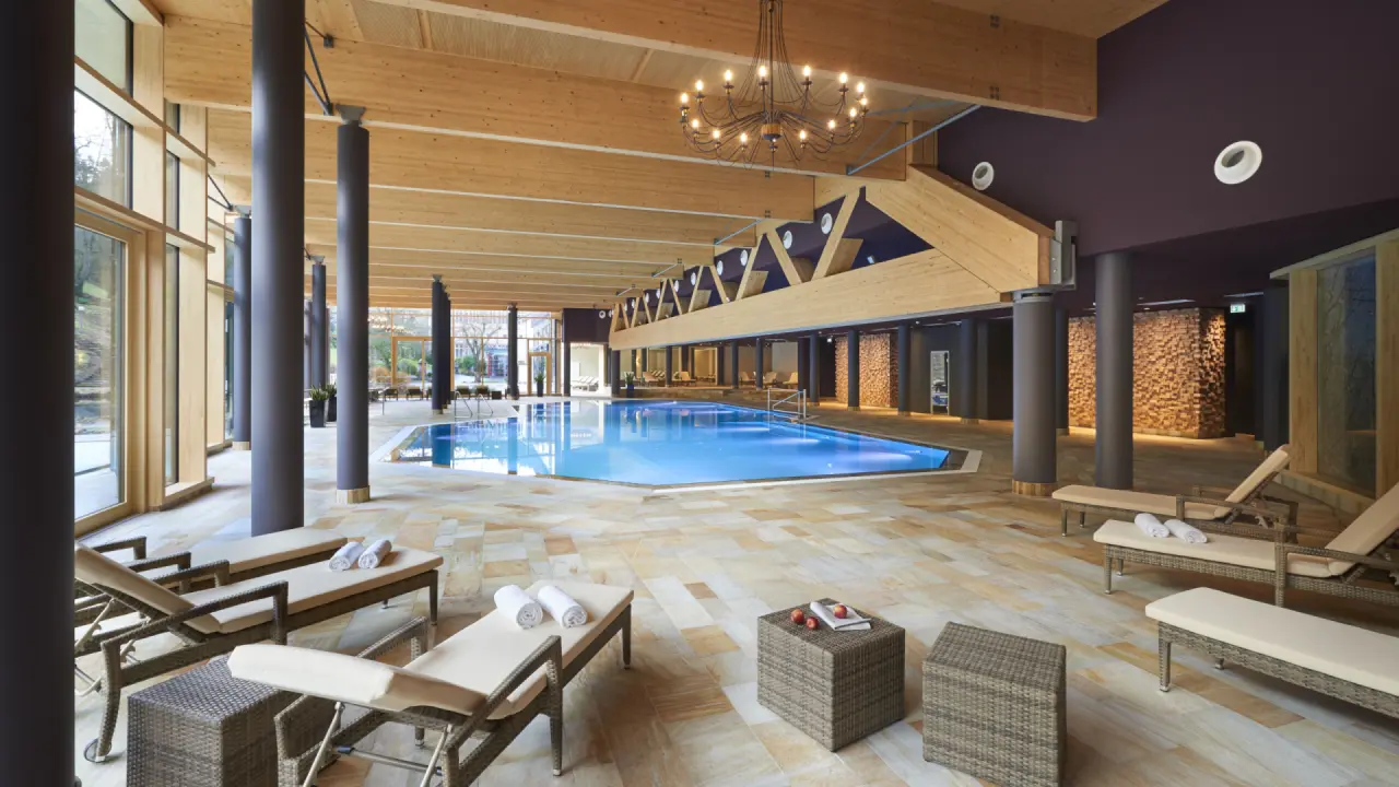 Grosszügiger Innenpoolbereich mit Holzarchitektur und grossen Fenstern im Hotel Therme Bad Teinach.