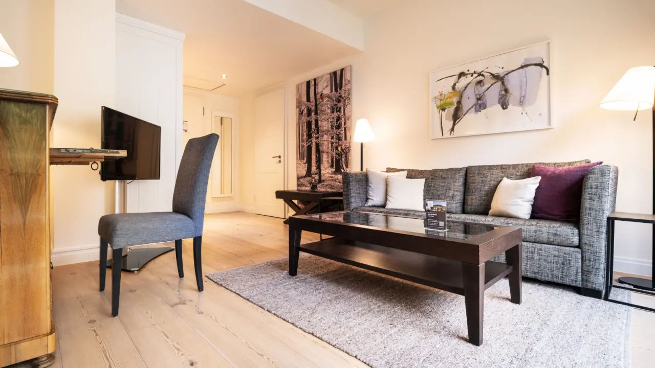 Gemütlicher Wohnbereich einer Suite im Hotel Therme Bad Teinach mit Sofa, Tisch und TV.