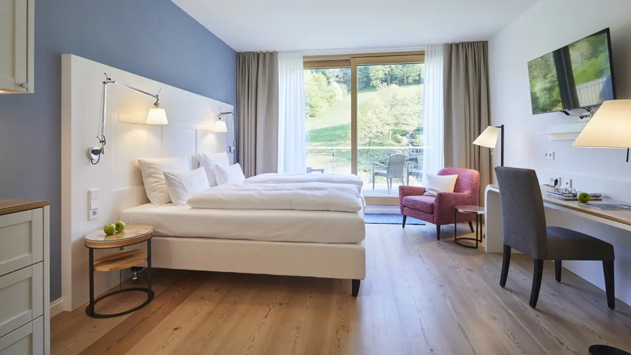Helles Hotelzimmer im Hotel Therme Bad Teinach mit Doppelbett, Balkon und Blick auf die Natur. Ideal zum Entspannen.