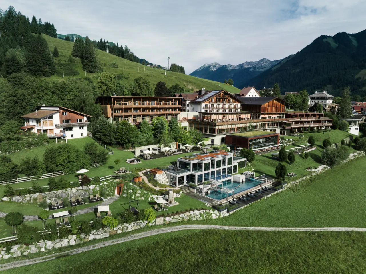 Luftaufnahme des Hotel Mohr Life Resort mit Aussenpools, weitläufigen Gärten und Alpenpanorama.