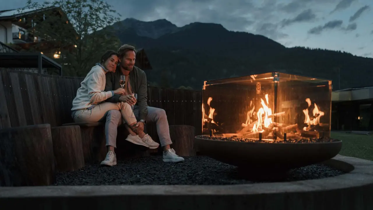 Romantischer Abend am modernen Feuerplatz mit einem Paar und Bergblick im Garten des Hotel Mohr Life Resort.