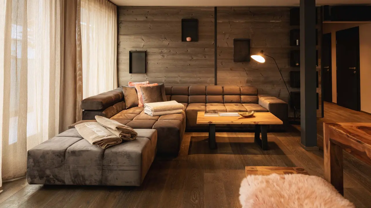 Gemütlicher Wohnbereich einer Suite im Hotel Mohr Life Resort mit Holzwänden, großem Sofa und warmem Licht.