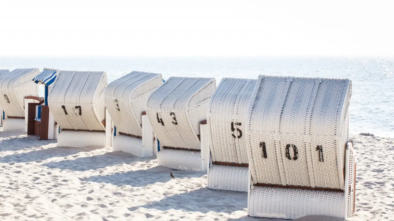 Reihe von weißen Strandkörben am Sandstrand mit Blick auf die Ostsee im Strandhotel Fischland.