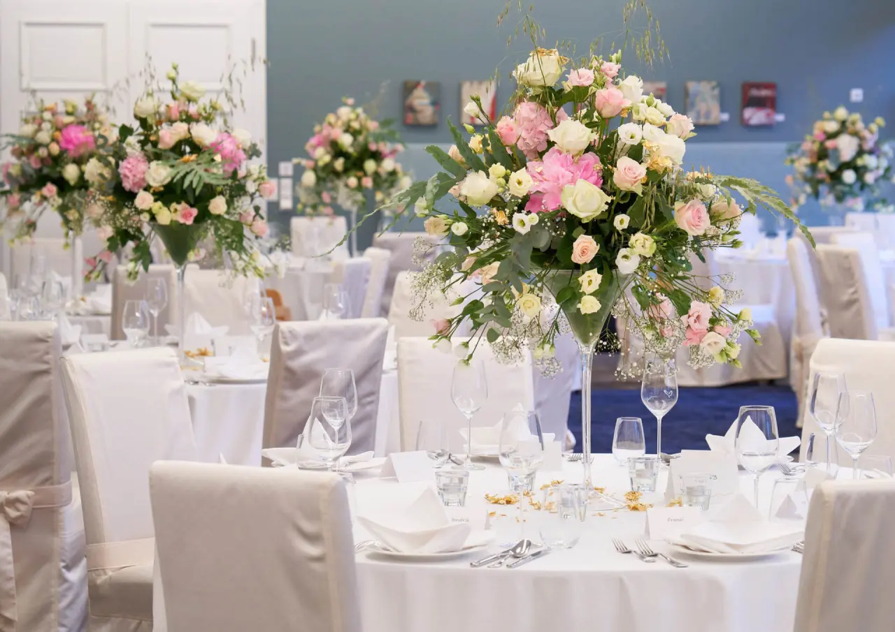 Elegant gedeckter Tisch mit rosa-weißen Blumenarrangements im Restaurant des Strandhotel Fischland.