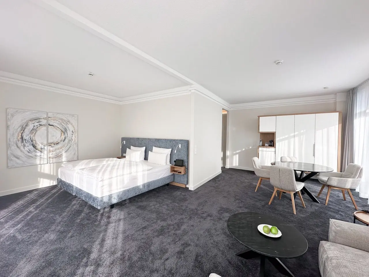 Geräumiges, modernes Hotelzimmer im Strandhotel Fischland mit Doppelbett, Sitzbereich und viel Tageslicht.