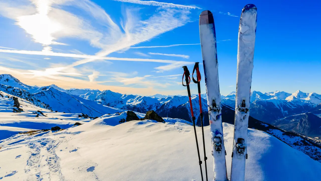Winterliches Bergpanorama mit Skiern und Skistöcken, ideal für Aktivurlaub im Hirschen Wohlfühlhotel.