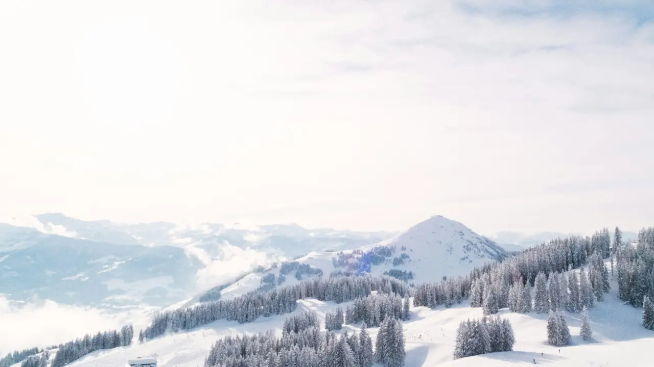 Winterliches Bergpanorama mit verschneiten Wäldern und Skipisten in der Umgebung des Hirschen Wohlfühlhotels.