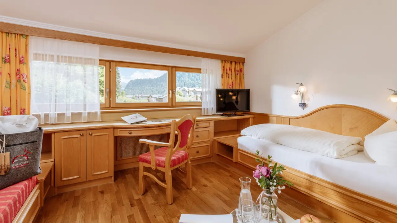 Gemütliches Hotelzimmer im Hirschen Wohlfühlhotel mit Schreibtisch, Einzelbett und Bergblick.