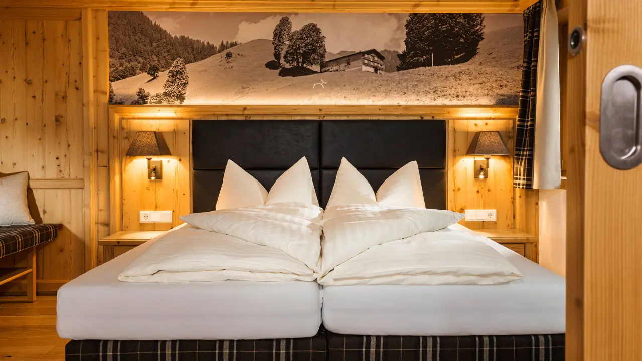 Gemütliches Doppelzimmer im alpinen Stil mit Holzwänden und Bergbild im Hirschen Wohlfühlhotel.