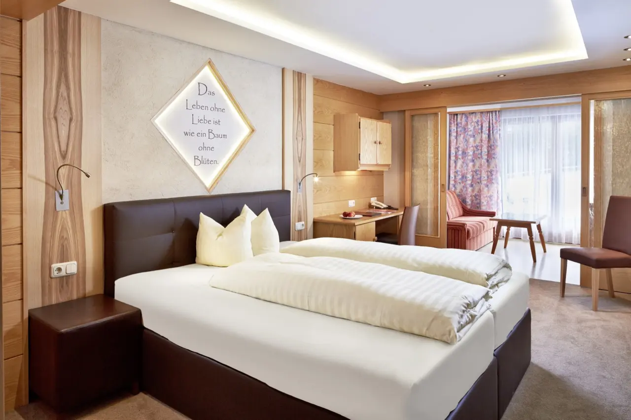 Gemütliches Doppelzimmer im Hotel TIROL mit Holzelementen, bequemen Betten und Balkonzugang.