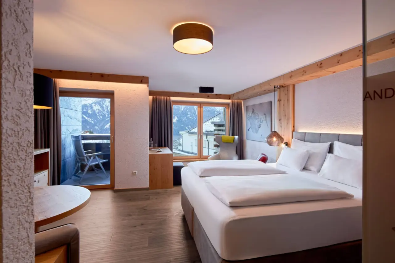 Gemütliches Doppelzimmer mit Holzelementen, Balkon und Bergblick im Hotel TIROL.