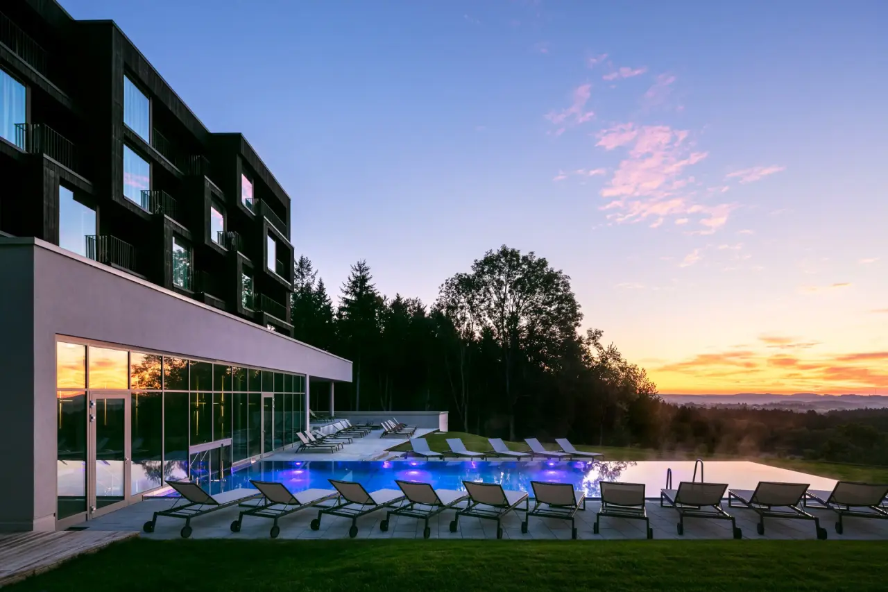 Beleuchteter Außenpool des Fritz Lauterbad Wellnesshotels bei Sonnenuntergang mit Blick auf die Landschaft.