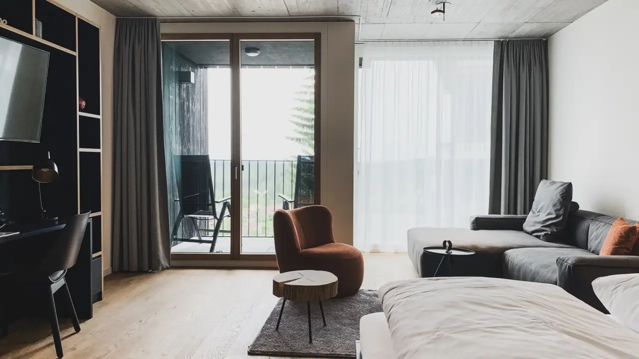 Modernes Hotelzimmer im Fritz Lauterbad Wellnesshotel mit gemütlichem Wohnbereich, Balkon und Blick ins Grüne.
