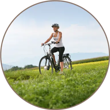 Aktive Erholung: Frau auf einem Fahrrad in grüner Natur mit Bergkulisse, ideal für Radtouren im Landhotel Moorhof.