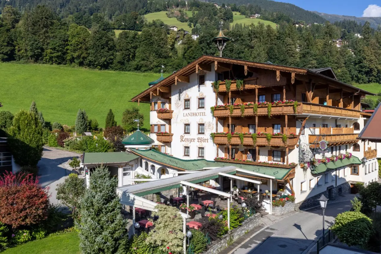 Traditionelles Landhotel Zenzerwirt mit blumengeschmückten Balkonen vor grüner Berglandschaft in Österreich.