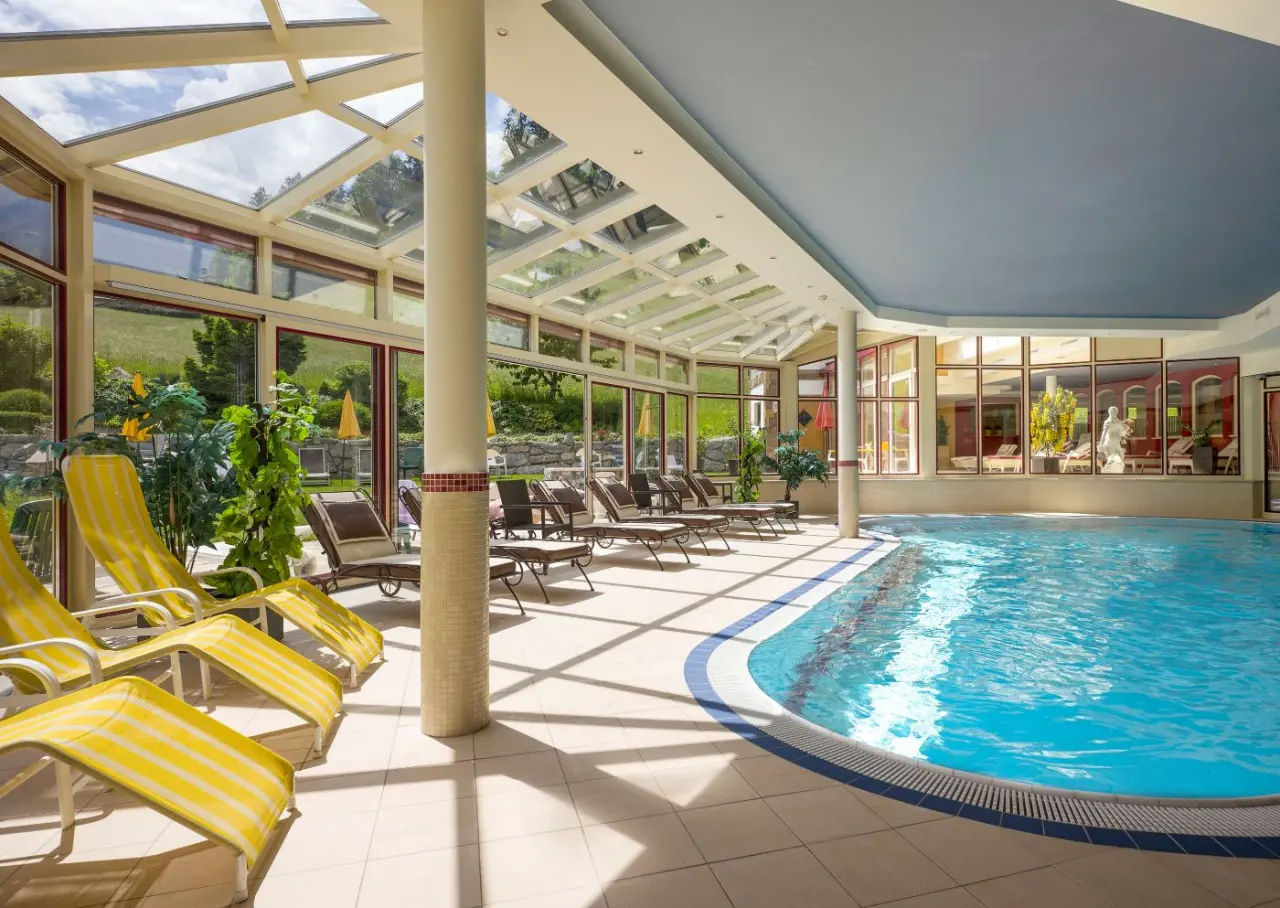 Helles Hallenbad mit grossen Fenstern und Liegestühlen im Landhotel Zenzerwirt, ideal zum Entspannen.