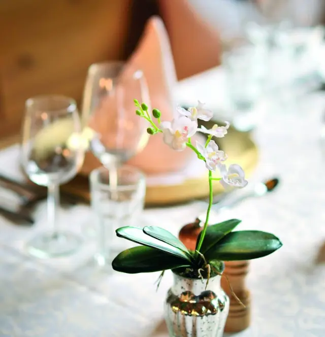 Alpenhotel Kindl in Neustift – Tischdekoration mit kleiner Orchidee und Weingläsern | Wellnesshotel Stubaital