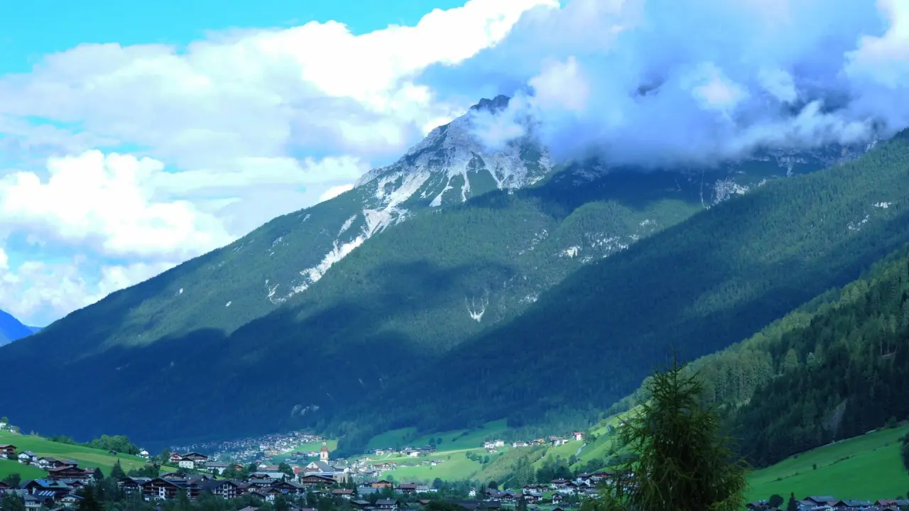 Malerisches Bergpanorama mit bewaldeten Hängen und einem idyllischen Dorf im Tal, nahe dem Alpenhotel Kindl.