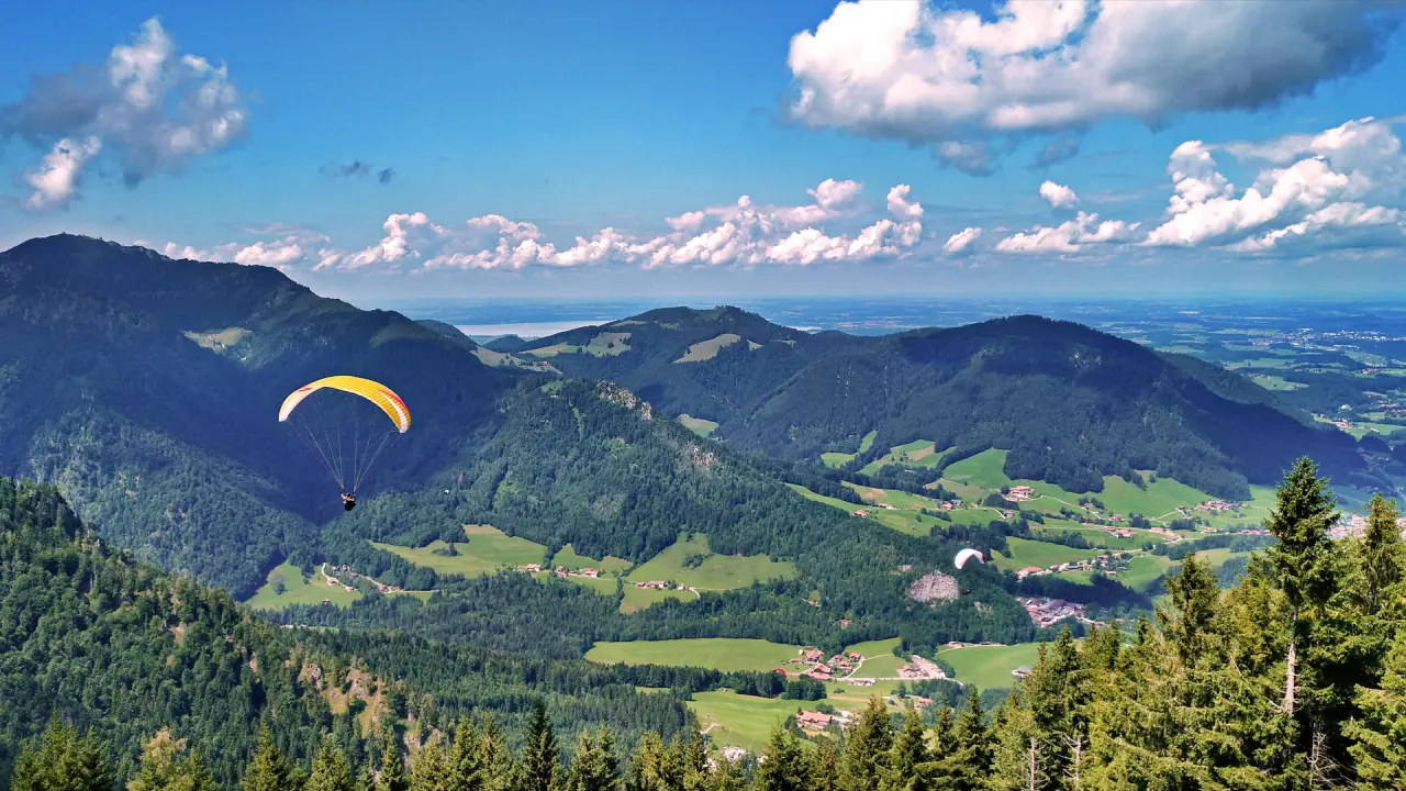 Spektakuläres Bergpanorama mit Paraglidern über grünen Tälern und einem See, nahe dem Wohlfühlhotel Ortnerhof.