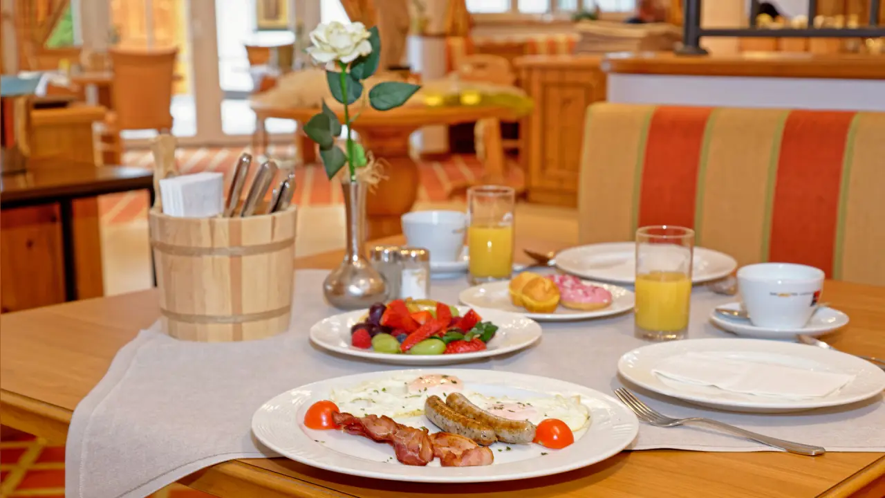 Frühstückstisch mit Spiegeleiern, Speck, Würstchen, frischem Obst und Saft im Restaurant vom Wohlfühlhotel Ortnerhof.