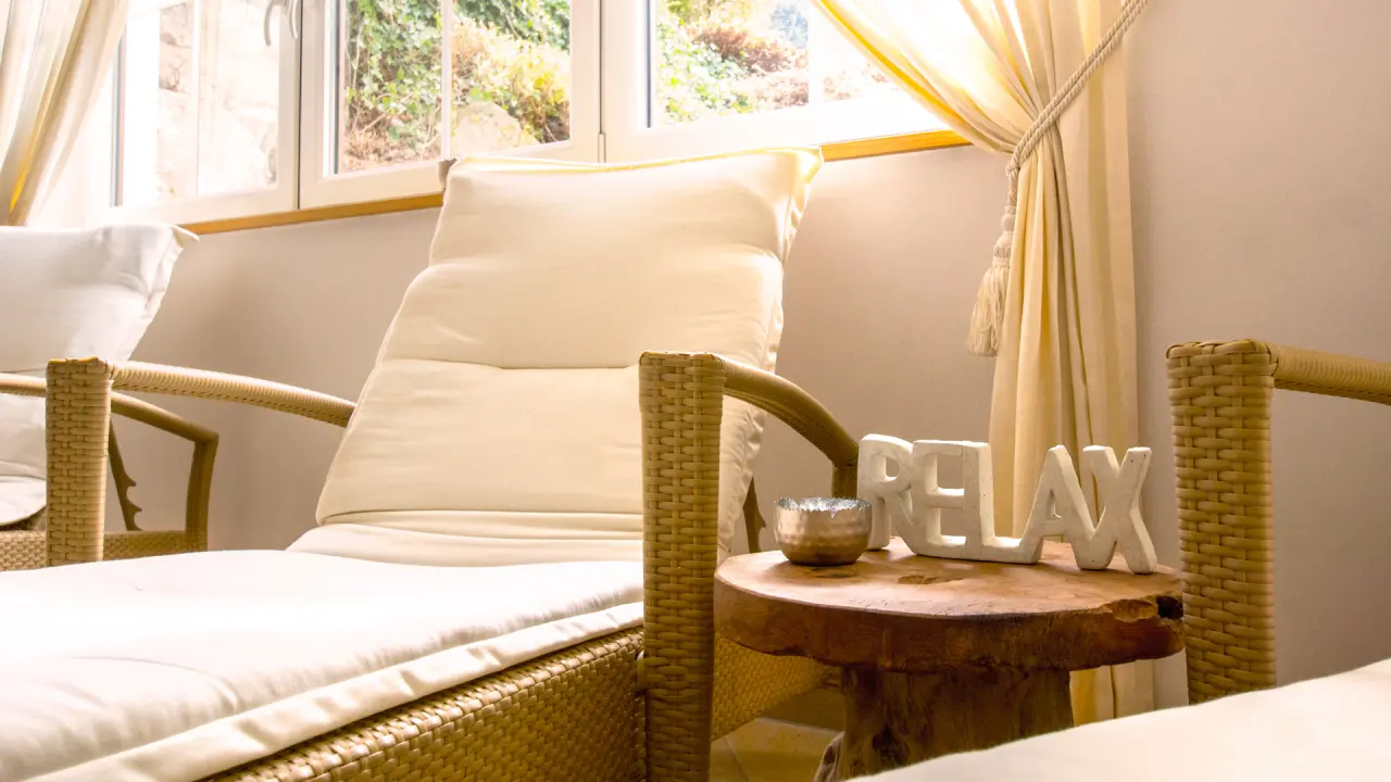 Gemütlicher Ruhebereich mit Rattanliegen und 'RELAX'-Schriftzug im Wellnessbereich des Wohlfühlhotels Ortnerhof.