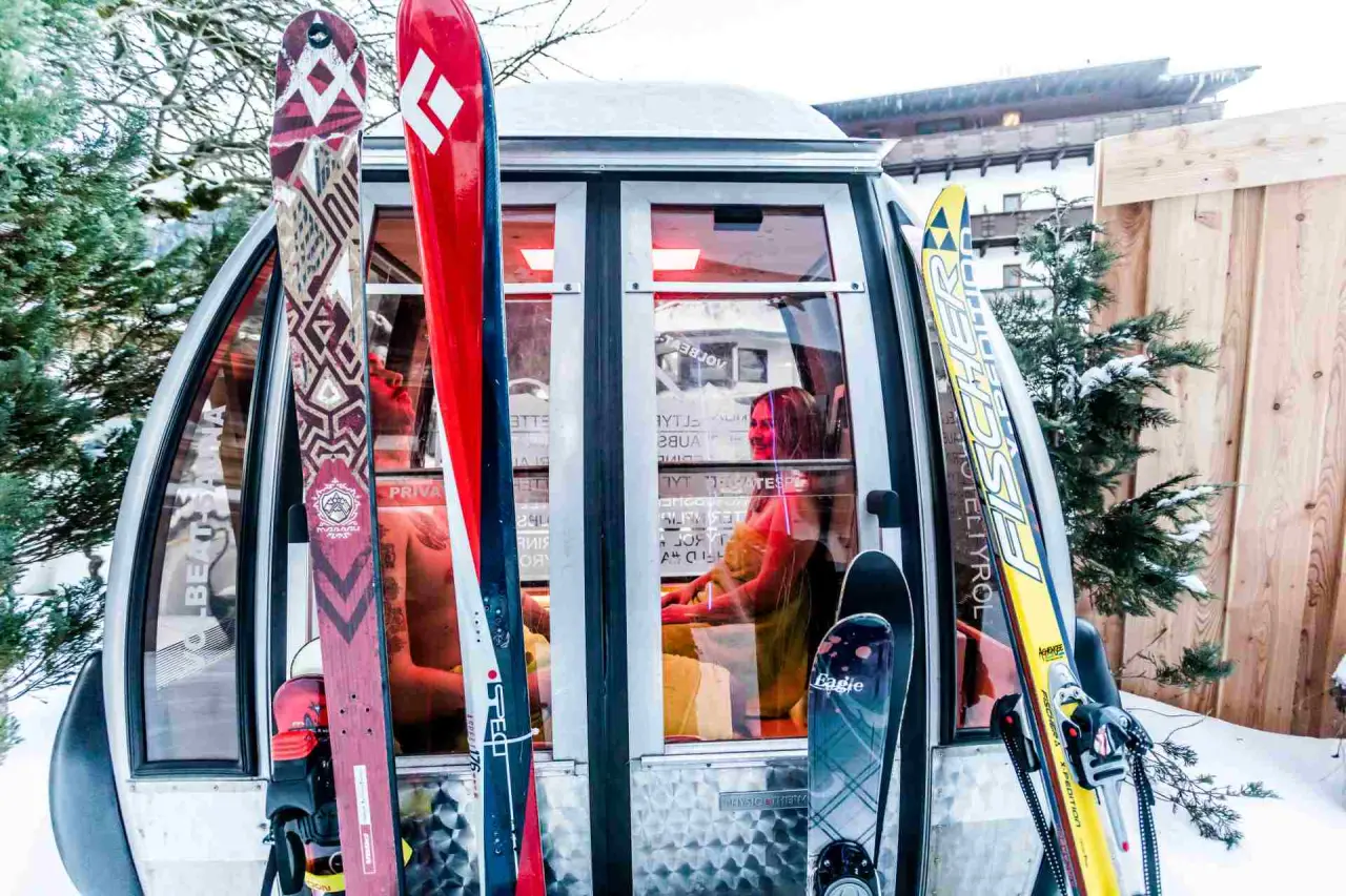Einzigartige Gondel-Lounge mit Skiern im Schnee vor dem Alpenhotel Tyrol am Achensee, ideal für Après-Ski Entspannung.