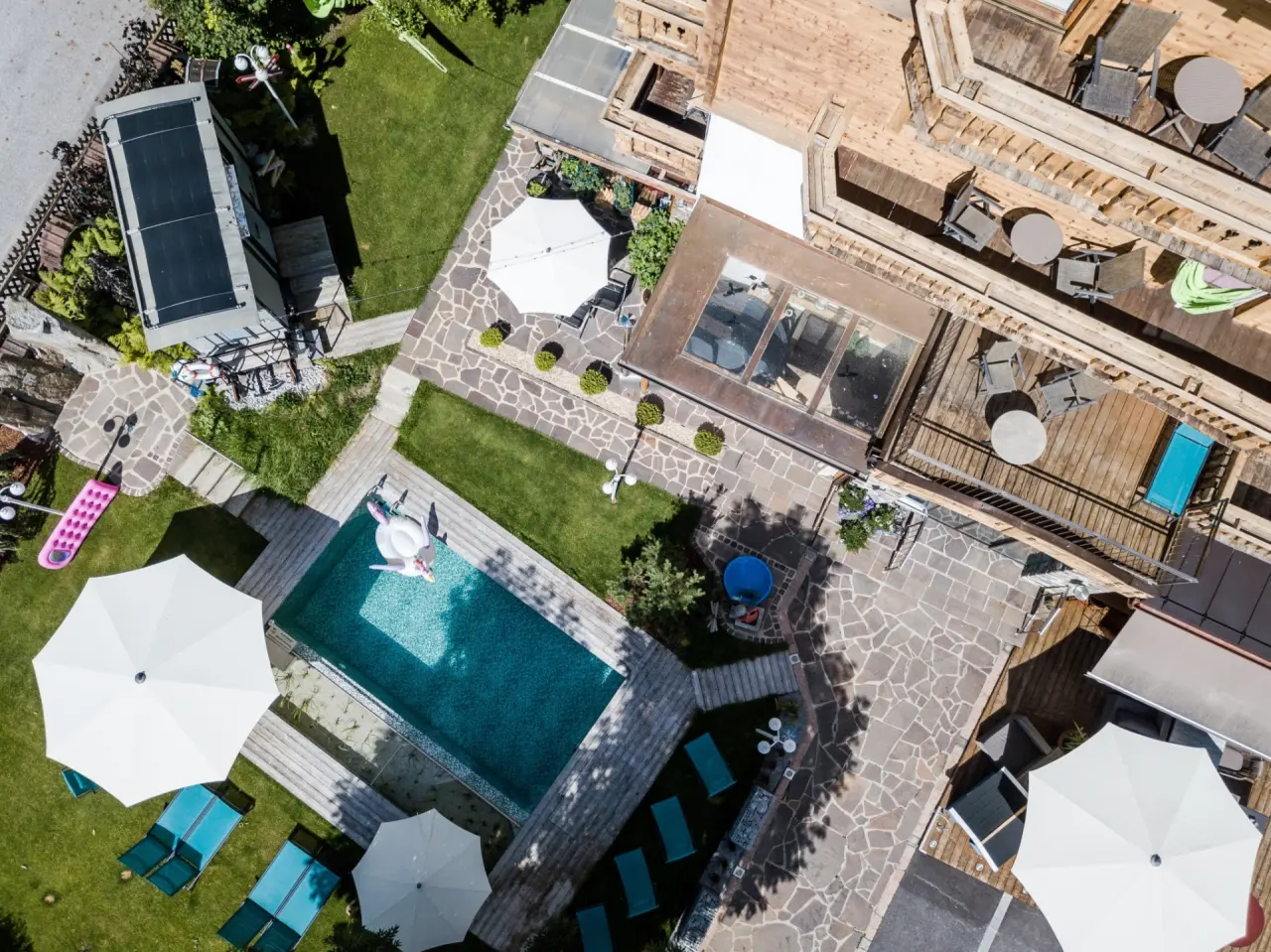 Luftaufnahme des Aussenpools mit Liegen, Garten und Terrassen des Alpenhotel Tyrol am Achensee.