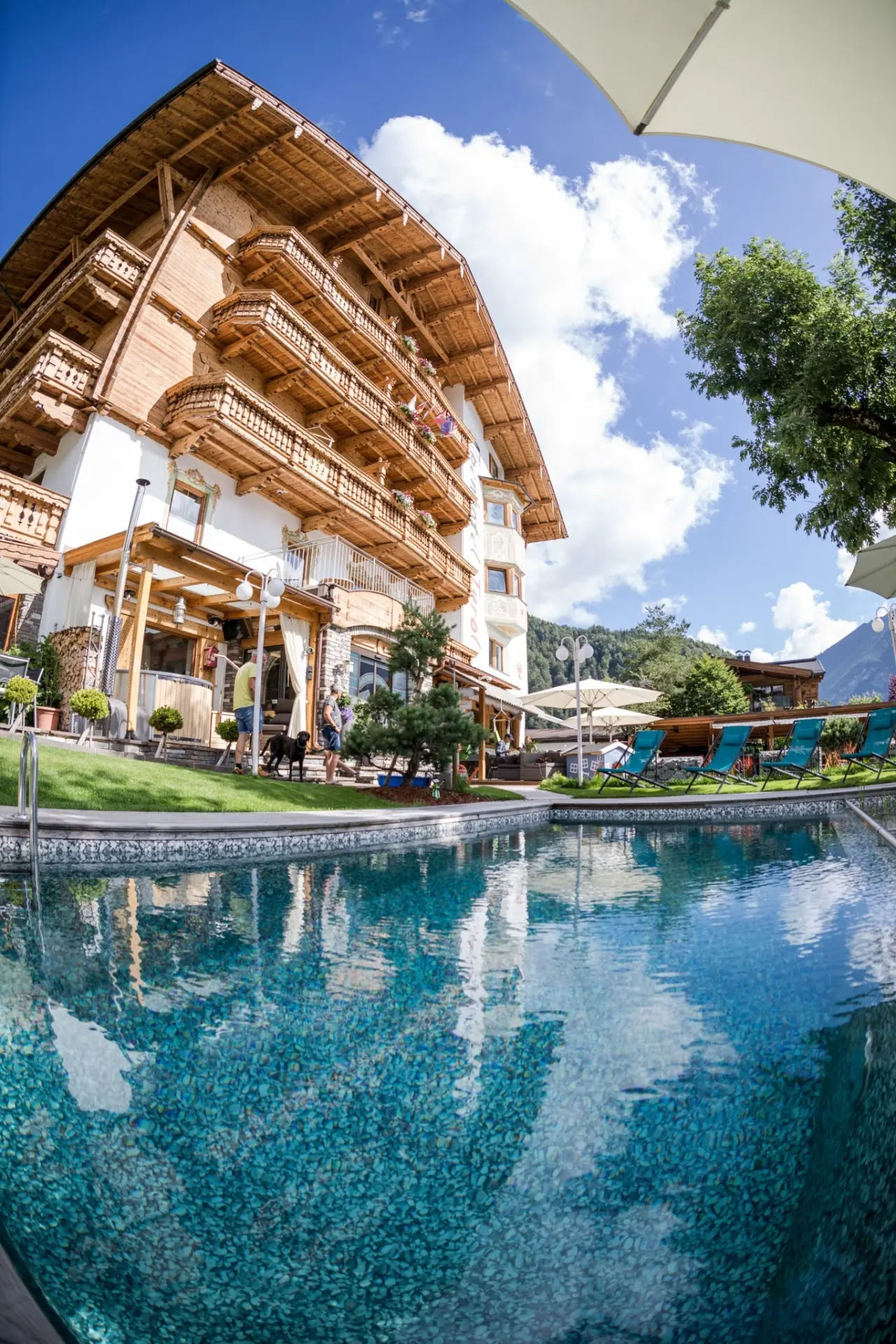 Aussenpool des Alpenhotel Tyrol am Achensee mit traditioneller Architektur und Bergpanorama.
