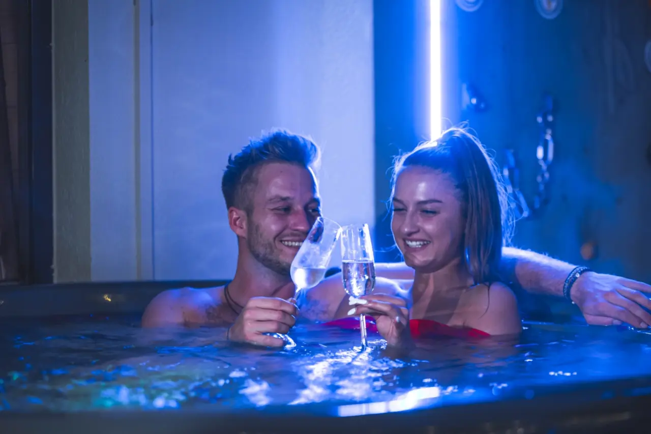 Romantisches Paar im beleuchteten Whirlpool des Alpenhotel Tyrol am Achensee genießt Sekt. Entspannung im Adults Only Spa.