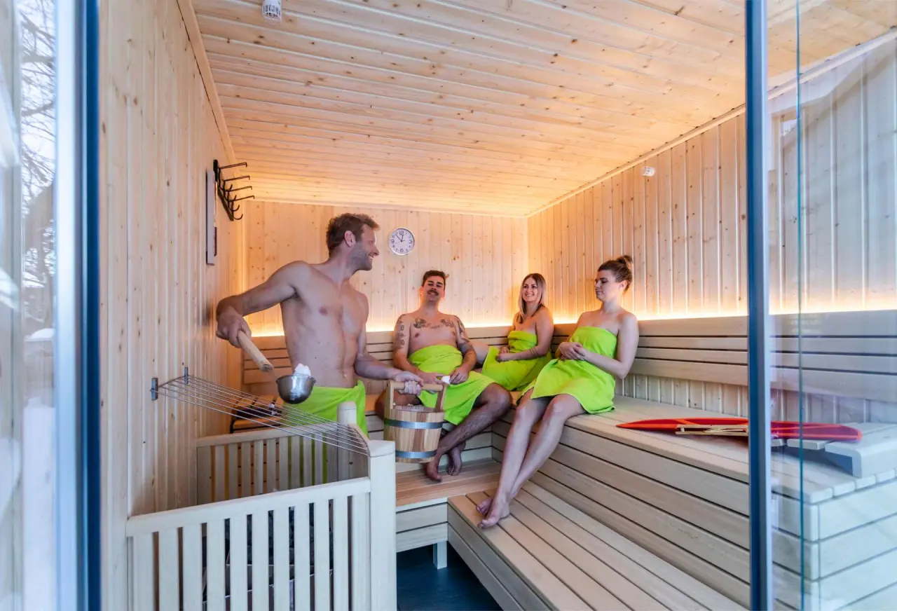 Gäste genießen einen entspannenden Aufguss in der modernen Holzsauna des Alpenhotel Tyrol am Achensee.
