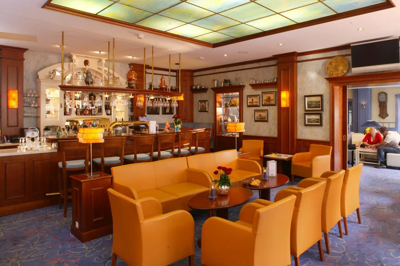 Gemütliche Hotelbar mit orangefarbenen Sitzgelegenheiten und beleuchteter Decke im Hotel Pabst.