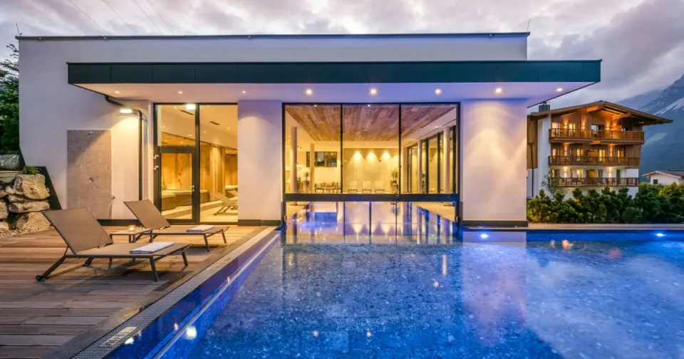 Abendliche Aussenansicht des beheizten Aussenpools und Spa-Bereichs im Hotel DER BÄR mit Alpenpanorama.