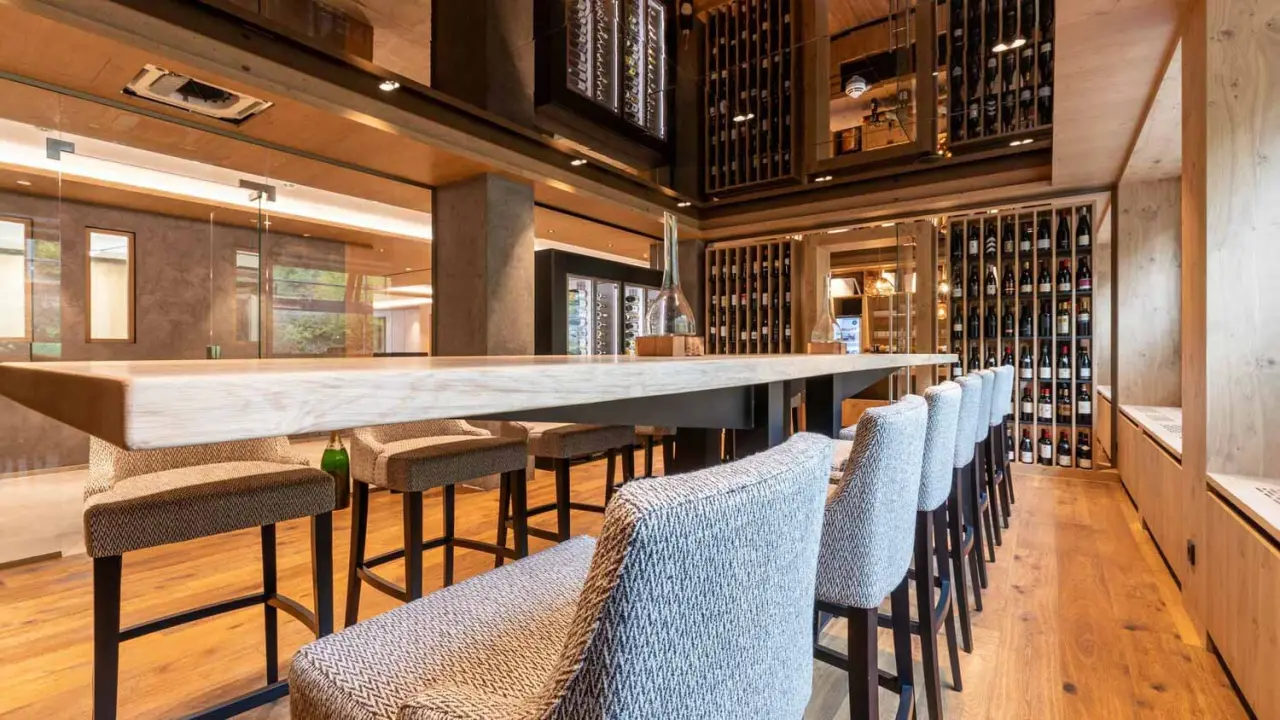 Moderne Weinbar im Genusshotel Sackmann mit langer Holztheke, bequemen Barhockern und eleganten Weinregalen.