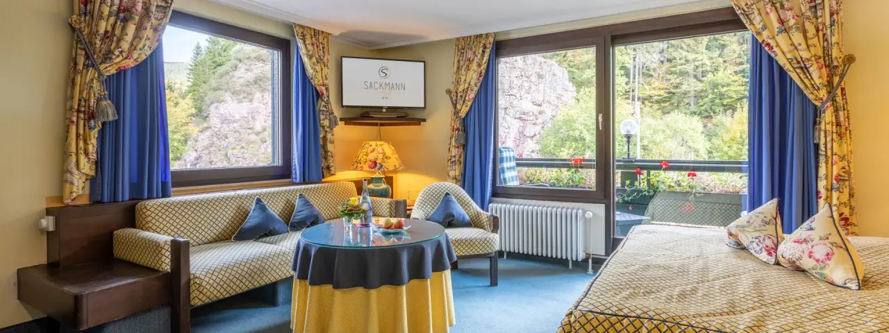 Komfortables Hotelzimmer im Genusshotel Sackmann mit gemütlichem Sitzbereich und Balkonblick auf die Natur.