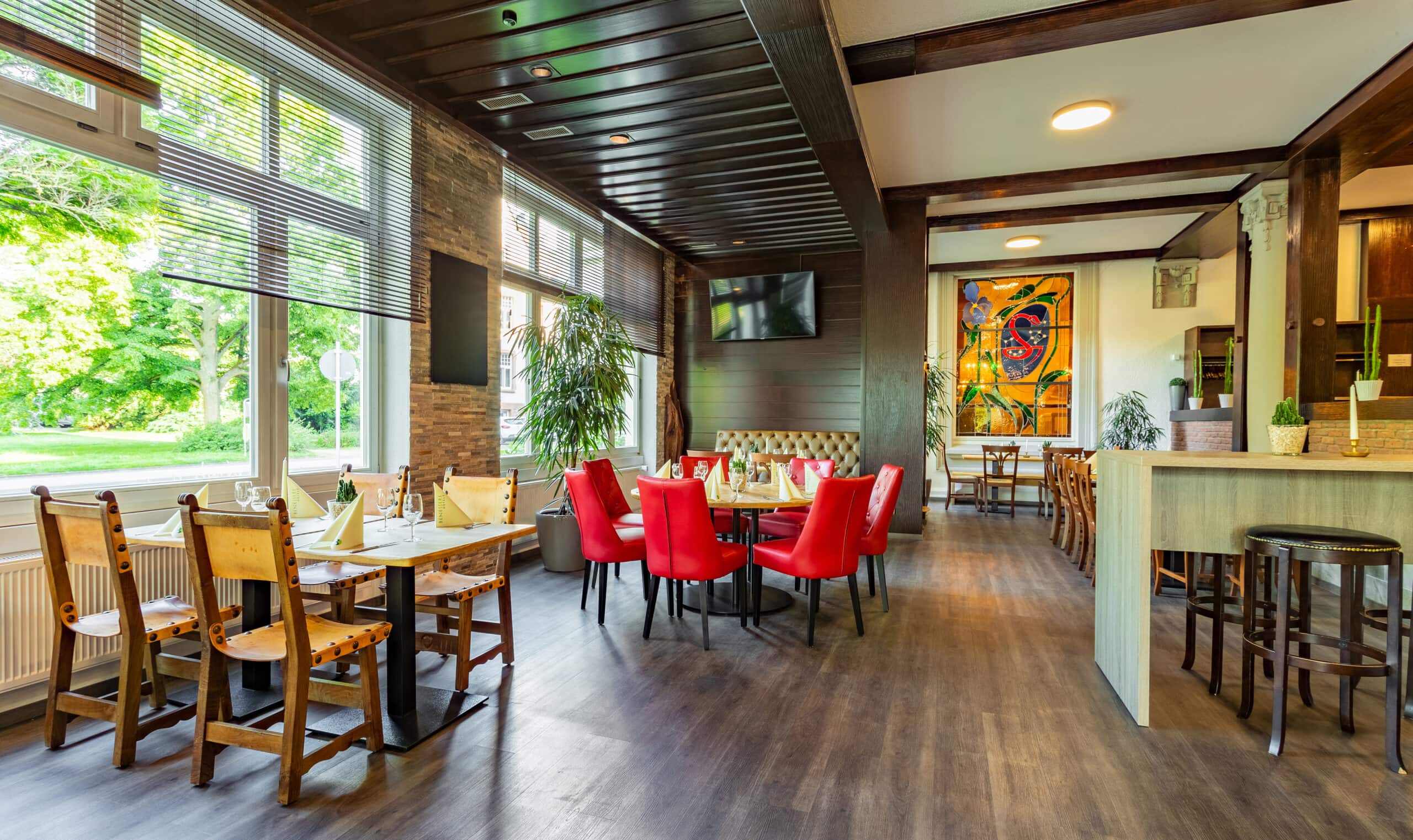 Hotel Badehof in Bad Salzschlirf – Helles Restaurant mit roten Stühlen und Blick ins Grüne | Wellnesshotel Hessen