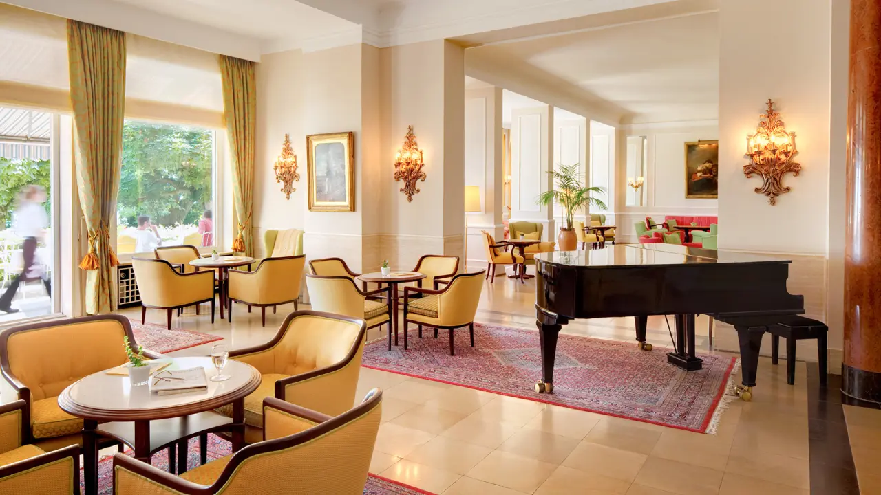 Elegante Hotellobby mit Flügel, gemütlichen Sitzbereichen und Blick ins Grüne im Hotel Bad Schachen.