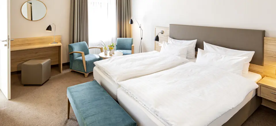 Gemütliches Doppelzimmer im Hotel Noltmann-Peters mit bequemen Betten, Sitzbereich und Schreibtisch.