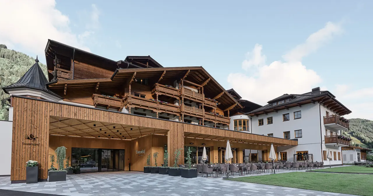 Moderne alpine Architektur des Hotel Tauernhof mit Holzfassade und einladendem Aussenbereich vor Bergkulisse.