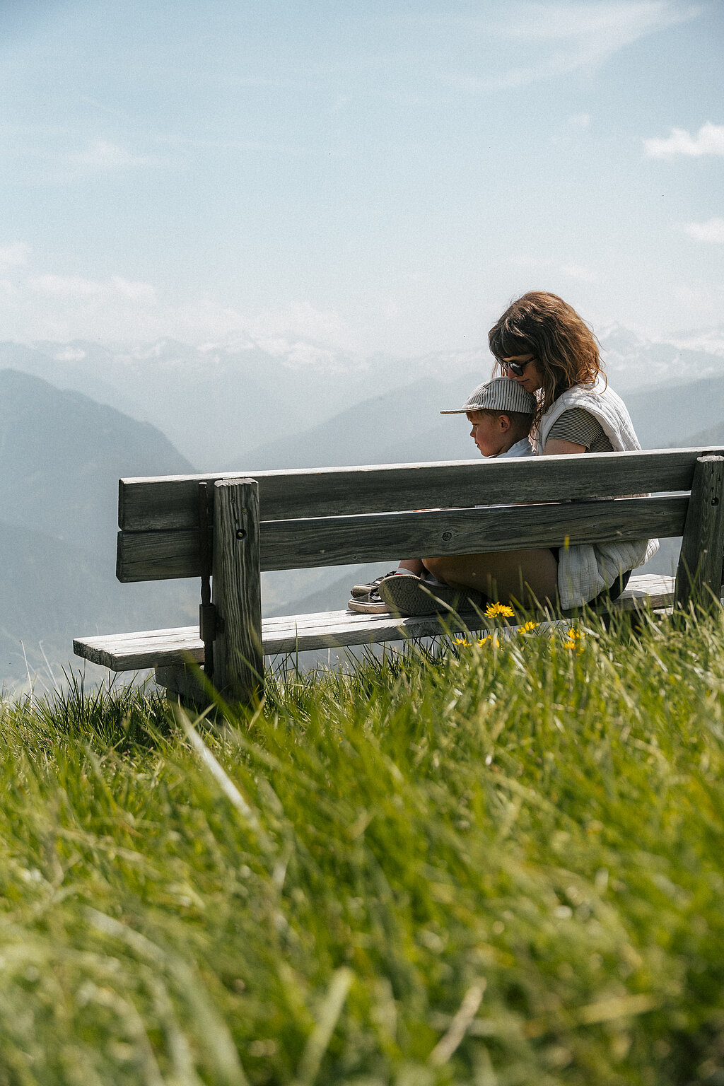 Hotel Tauernhof in Großarl – Familie auf einer Holzbank mit weitem Blick über die Alpen | Wellnesshotel Salzburger Land