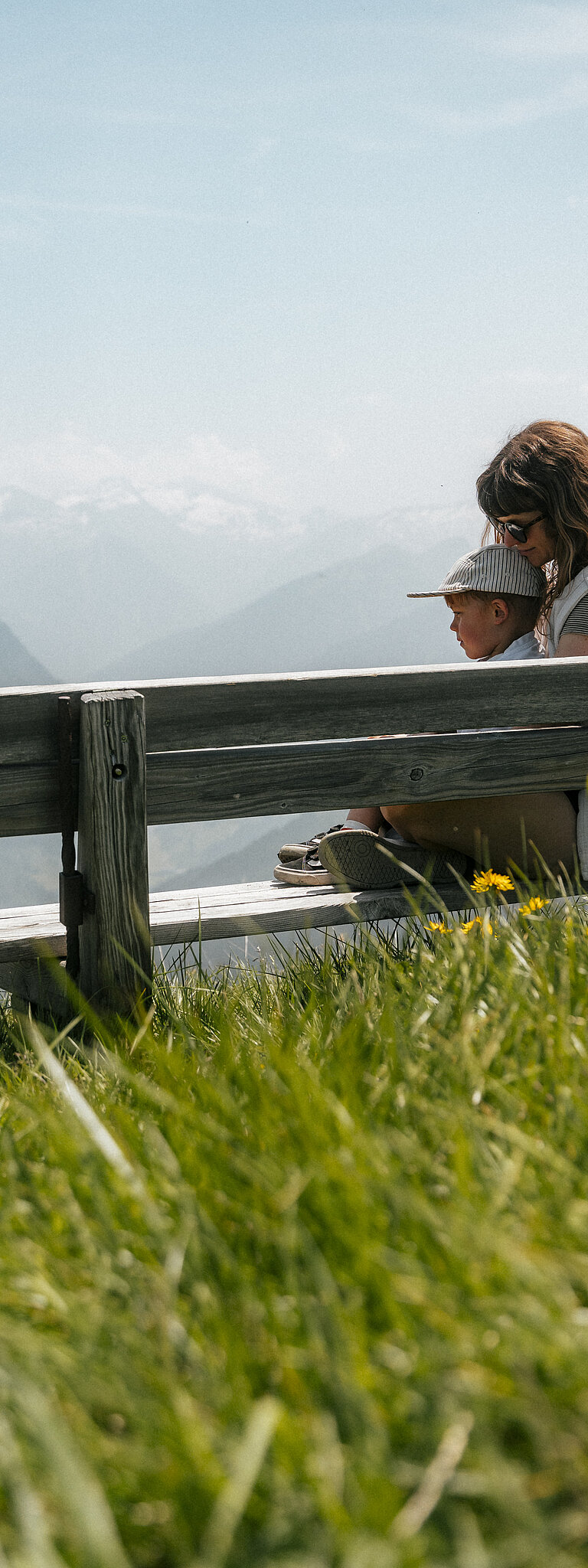 Hotel Tauernhof in Großarl – Mutter und Kind entspannen auf einer Bank mit Bergblick | Wellnesshotel Salzburger Land