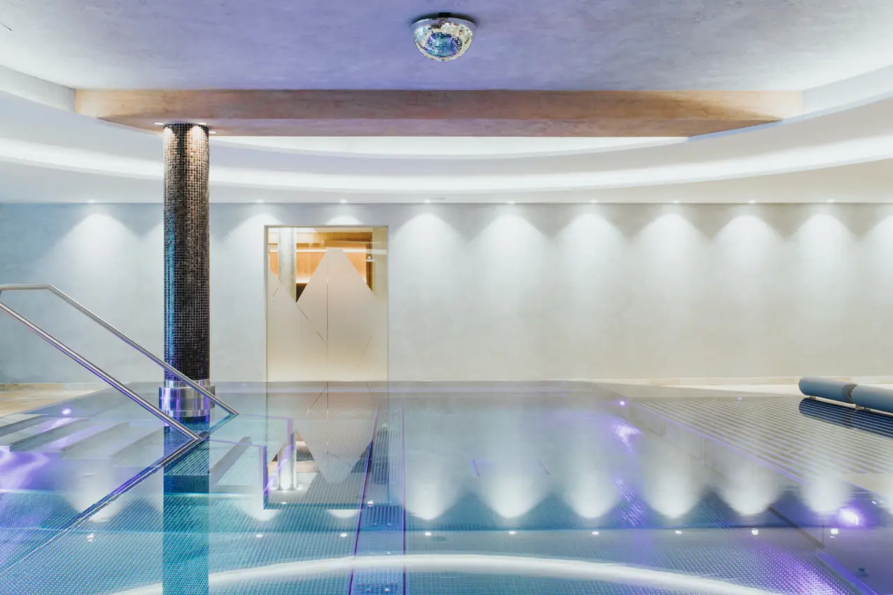 Modernes Hallenbad mit stilvoller Beleuchtung und Mosaiksäule im Hotel Tauernhof