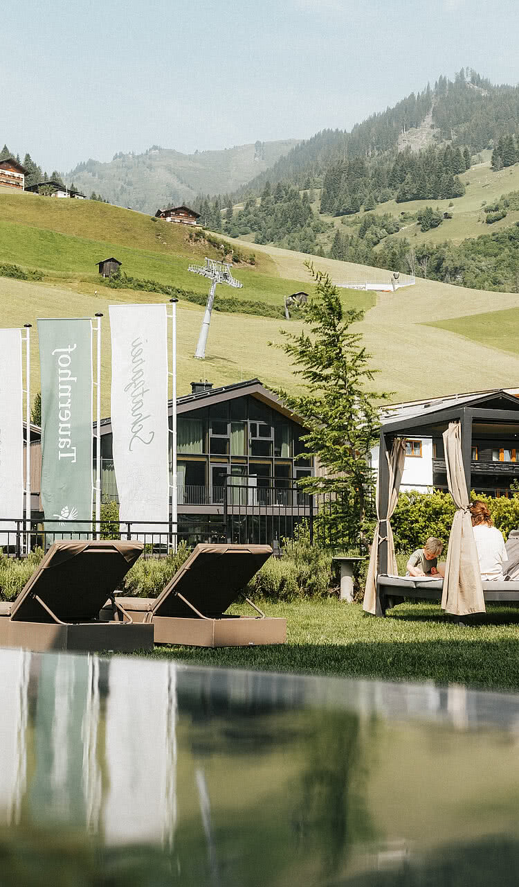 Hotel Tauernhof in Großarl – Infinity-Außenpool mit Liegen und Bergblick | Wellnesshotel Salzburger Land