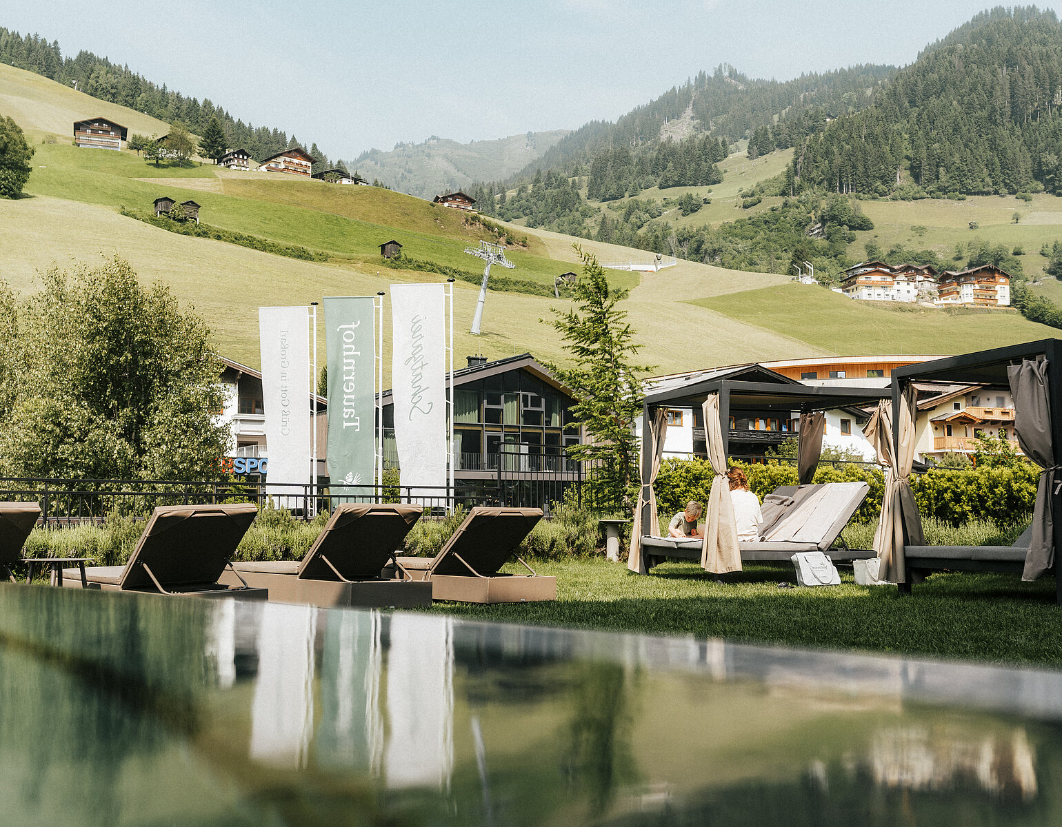 Hotel Tauernhof in Großarl – Infinity-Außenpool mit Liegen und Bergblick | Wellnesshotel Salzburger Land