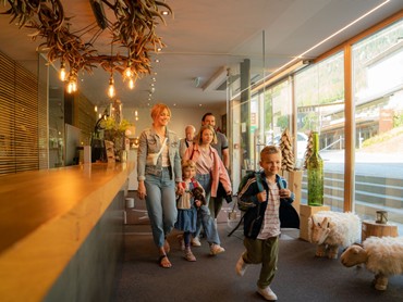 Familie beim Check-in in der modernen Lobby des VALAVIER Aktivresorts mit freundlichem Empfangsbereich.