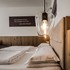 Gemütliches Doppelbett mit Holzdetails und moderner Beleuchtung im Zimmer des VALAVIER Aktivresort.