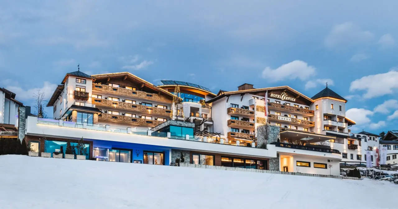 Beleuchtetes Wellness Hotel Cervosa in Serfaus im Winter bei Dämmerung, mit Schnee und alpiner Architektur.