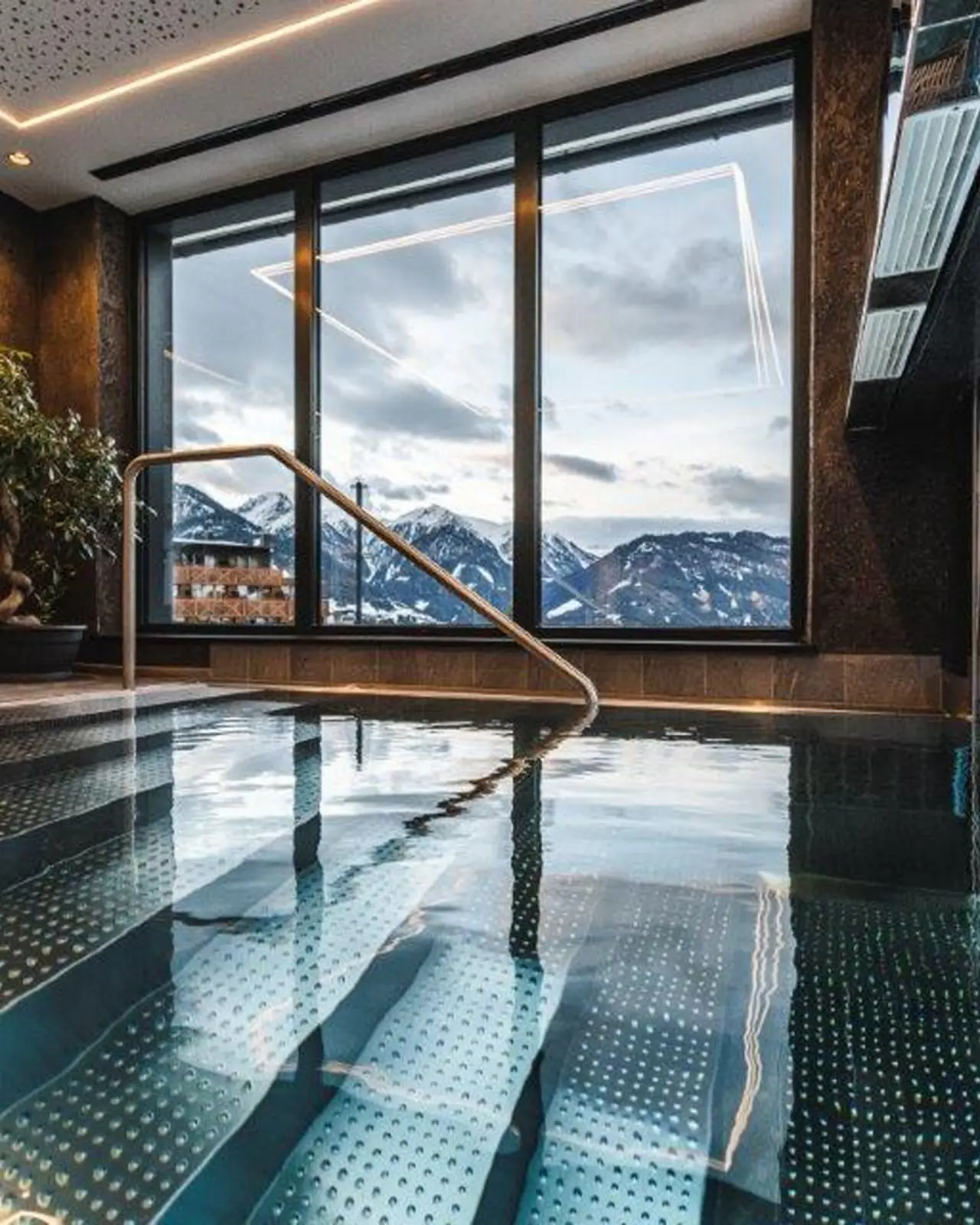 Innenpool mit grosser Fensterfront und Panoramablick auf die verschneiten Berge im Wellness Hotel Cervosa*****