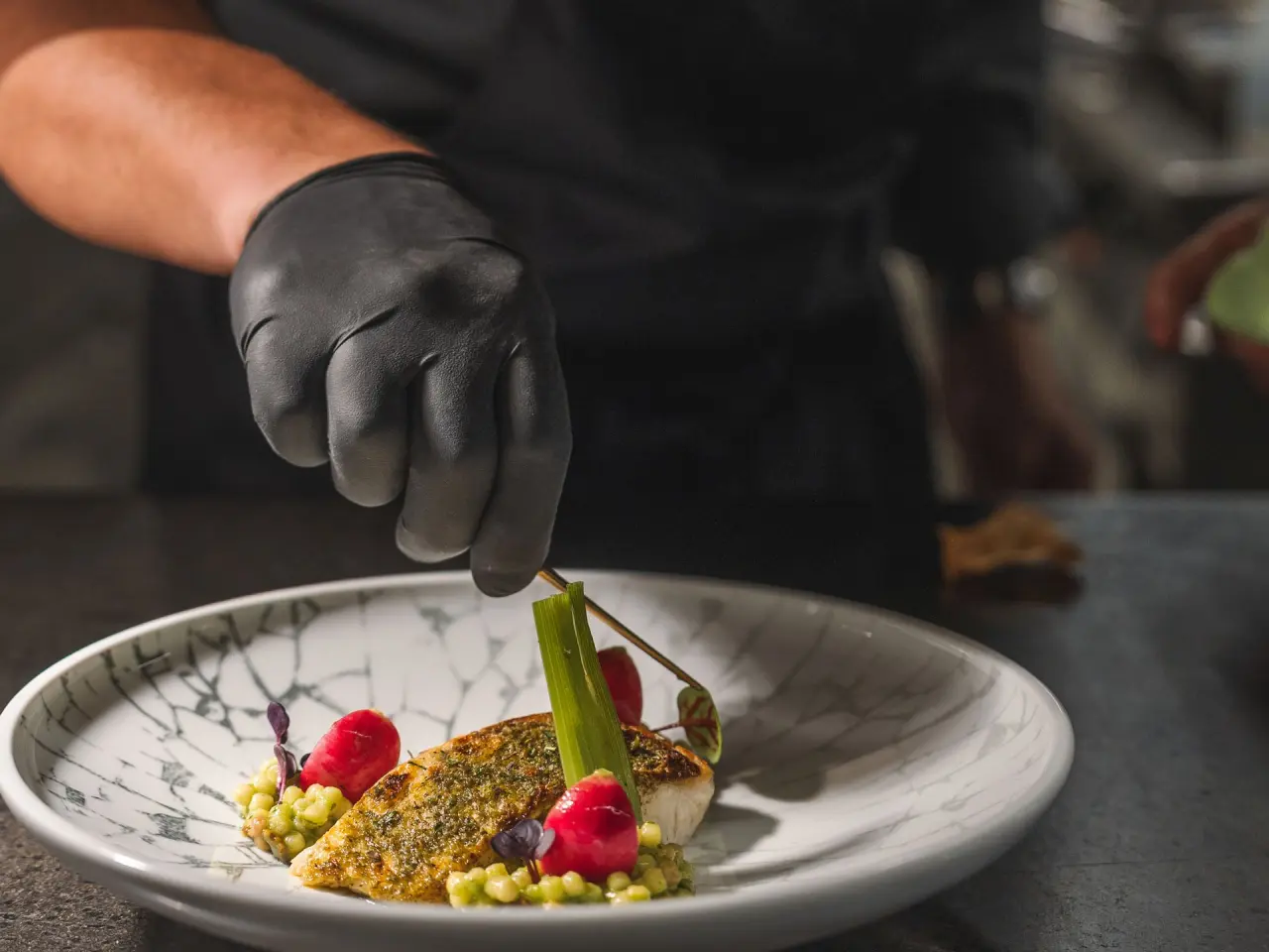 Koch garniert ein exquisites Gourmetgericht im Restaurant des Wellness Hotel Cervosa*****.