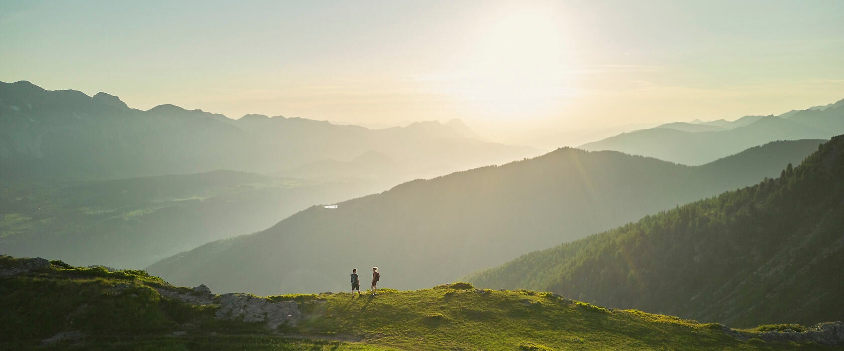Natur- und Wellnesshotel Höflehner in Haus – Wanderer auf Berggipfel mit weitem Alpenpanorama | Wellnesshotel Steiermark